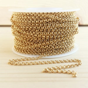 May include: A spool of gold-colored chain, with a few inches of chain uncoiled on a wooden surface.