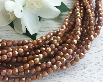 May include: A strand of faceted glass beads in a warm, reddish-brown color. The beads have a shimmery, iridescent finish.