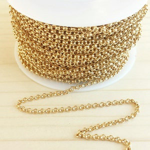 May include: A spool of gold-colored chain, with a small section of the chain uncoiled and lying on a wooden surface.
