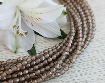 May include: A strand of metallic brown faceted glass beads. The beads are small and have a shiny finish.