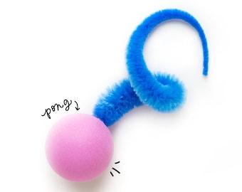 Peut inclure: Une boule de pompon rose attachée à un cure-pipe bleu enroulé en spirale. Le texte "pong?" est écrit au-dessus de la boule.