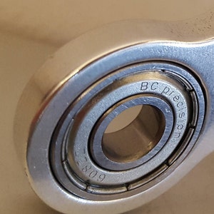 May include: Close-up of a silver metal bearing with the text "BC Precision" and the number "809" engraved on the side.