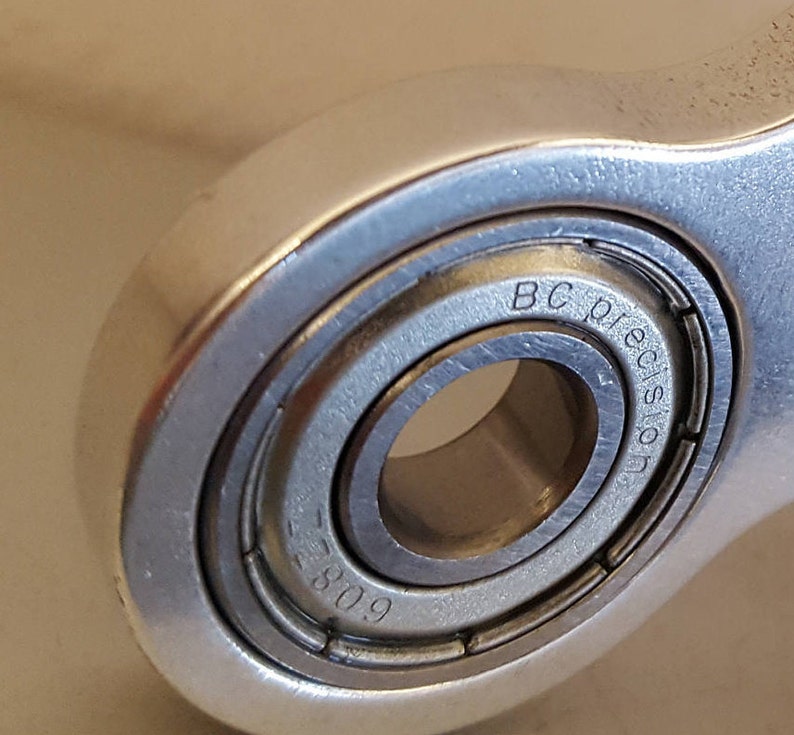 May include: Close-up of a silver metal bearing with the text "BC Precision" and the number "809" engraved on the side.