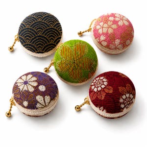 May include: Five round, zipped coin pouches featuring textured fabric with various patterns, including blue wave, pink cherry blossom, green floral, purple chrysanthemum, and red floral designs, each with a small gold-toned ball zip pull.