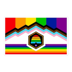 May include: A colorful flag with a rainbow beehive in the center. The flag has a white background with a rainbow stripe at the top and bottom. The beehive is surrounded by a black hexagon.