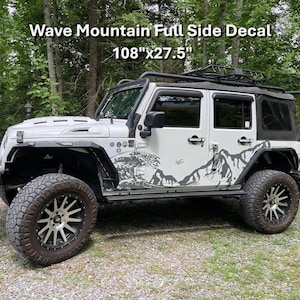 May include: White Jeep with a black roof and mountain-themed side decals. The decals are gray and black and feature a mountain range design. The text "Wave Mountain Full Side Decal" is visible, with dimensions of 108"x27.5".