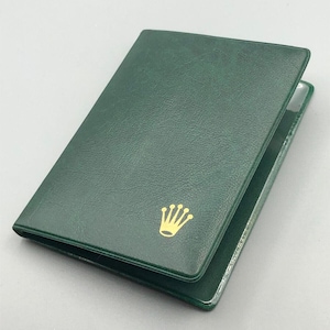 May include: A green leather watch box with a gold crown logo.