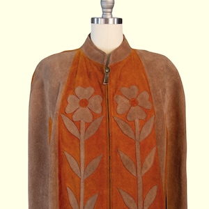 May include: A brown and orange suede jacket featuring a stand-up collar and a full-length front zipper. The front panels are decorated with large, appliqu&eacute;d brown flower motifs with long stems and leaves centered on the vibrant orange suede sections.