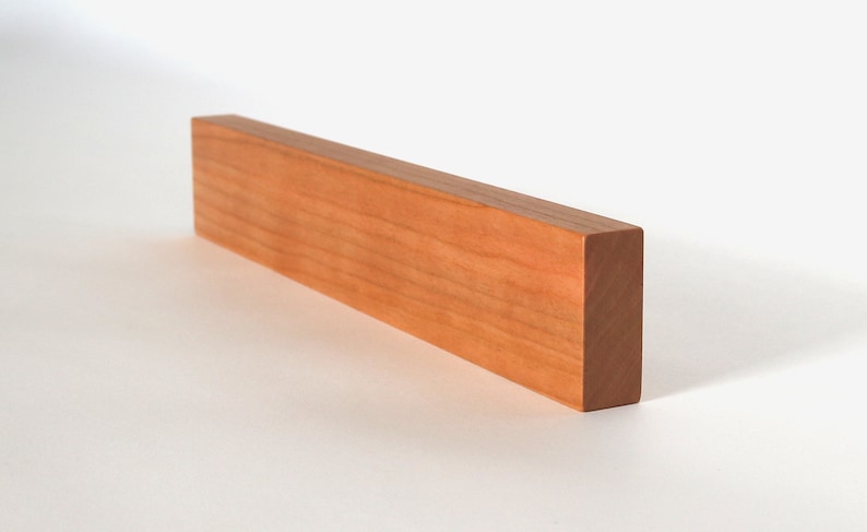 May include: A long, rectangular wooden block with a smooth, light brown finish. The block is made of cherry wood and has a natural grain pattern.