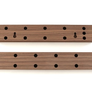 May include: Two wooden wall mounted organizers with multiple holes for hanging items. The larger organizer is approximately 18 inches long and the smaller organizer is approximately 9 inches long.