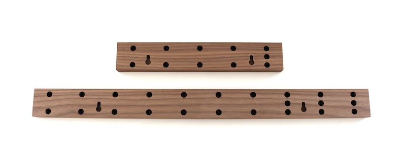 May include: Two wooden wall mounted organizers with multiple holes for hanging items. The larger organizer is approximately 18 inches long and the smaller organizer is approximately 9 inches long.