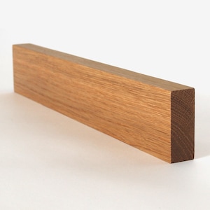 May include: A long, rectangular piece of light brown wood. The wood has a natural grain pattern and is smooth to the touch.
