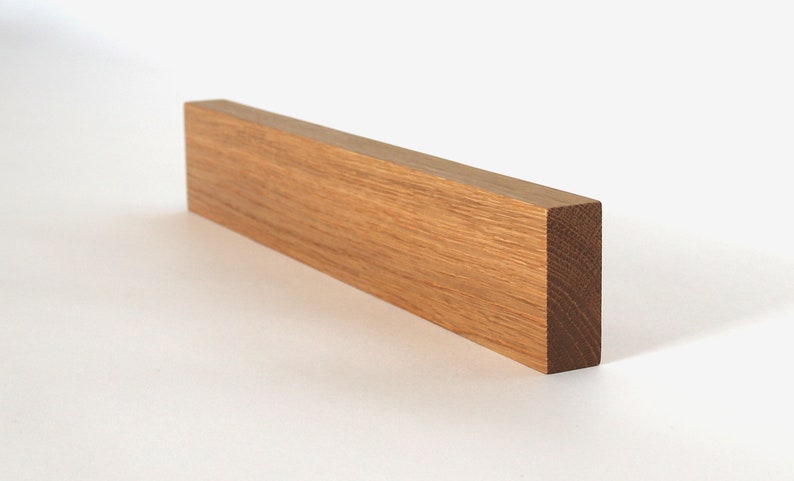 May include: A long, rectangular piece of light brown wood. The wood has a natural grain pattern and is smooth to the touch.