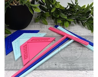 Pode incluir: Quatro réguas de plástico azuis, cor-de-rosa e azul claro com o texto "MSCraftshop" impresso nelas. As réguas estão empilhadas sobre uma superfície de madeira.