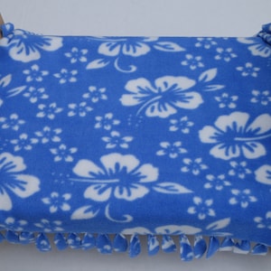 May include: A blue and white floral patterned fleece blanket with fringe on the edges is placed on a wooden bed frame.