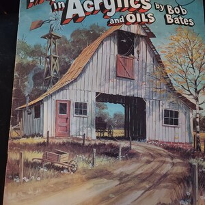 May include: A vintage book cover titled "More Adventures in Acrylics and Oils" by Bob Bates. The cover art depicts a rural scene with a barn, windmill, and dirt road. The book is published by Walter T. Foster.