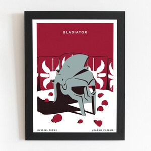 Könnte beinhalten: Ein minimalistisches Poster mit rotem Hintergrund und weißem Rand. Das Poster zeigt einen silbernen Gladiatorenhelm mit Schatten. Der Text "GLADIATOR" befindet sich oben auf dem Poster. Die Namen "RUSSELL CROWE" und "JOAQUIN PHOENIX" befinden sich unten auf dem Poster.