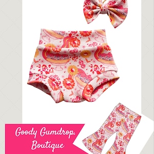 May include: A set of children's clothing featuring a high-waisted diaper cover, a matching bow, and a pair of flared pants. The items are adorned with a repeating pattern of red flowers, birds, and other elements on a cream background. The text "Goody Gumdrop Boutique" is displayed.