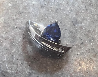 May include: A silver ring with a blue gemstone set in a prong setting. The ring has a curved band with a diamond accent.