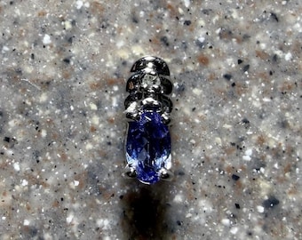 May include: A silver-toned pendant featuring an oval-cut blue gemstone at the base, topped with a smaller, clear, round-cut stone set within a tiered, metallic structure that has a polished, reflective finish and a smooth, curved design.