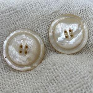May include: Two white mother-of-pearl buttons with two holes each.