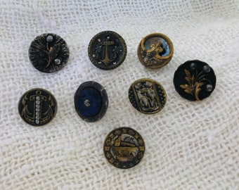 Puede incluir: Ocho botones vintage con varios diseños, incluyendo anclas, flores y un timón de barco. Los botones están hechos de metal y tienen un aspecto desgastado y antiguo.