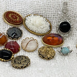 Può includere: Assortimento di bottoni e ciondoli vintage in vari colori e materiali, tra cui un cammeo bianco, un ciondolo in onice nero e un bottone in agata rossa.