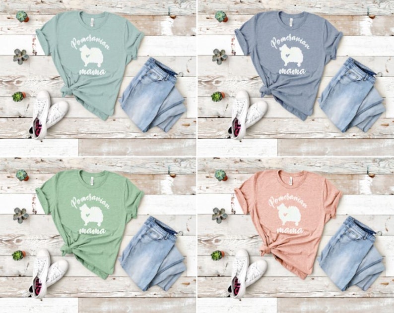 May include: Four different color t-shirts with a white Pomeranian silhouette and the text "Pomeranian mama" on the front. The shirts are displayed on a light wood background with blue jeans and white sneakers.