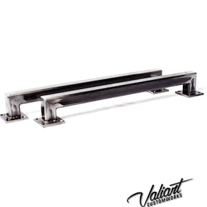 May include: Two silver metal door handles with square ends. The handles are long and rectangular, with a slight curve in the middle. The handles are made of a brushed metal and have a matte finish.