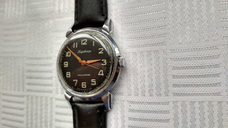 Pu&ograve; includere: Un orologio da polso con quadrante nero, cassa argentata e cinturino in pelle nera. Il quadrante dell'orologio ha numeri bianchi e una lancetta dei secondi rossa. Il marchio dell'orologio &egrave; "Slava" e il testo "USSR Made" &egrave; stampato sul quadrante.