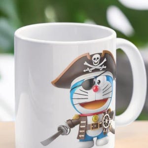 May include: White ceramic mug featuring a cartoon character dressed as a pirate. The character is blue with a red nose, wearing a brown pirate hat with a skull and crossbones, and holding a sword. The mug has a white handle.