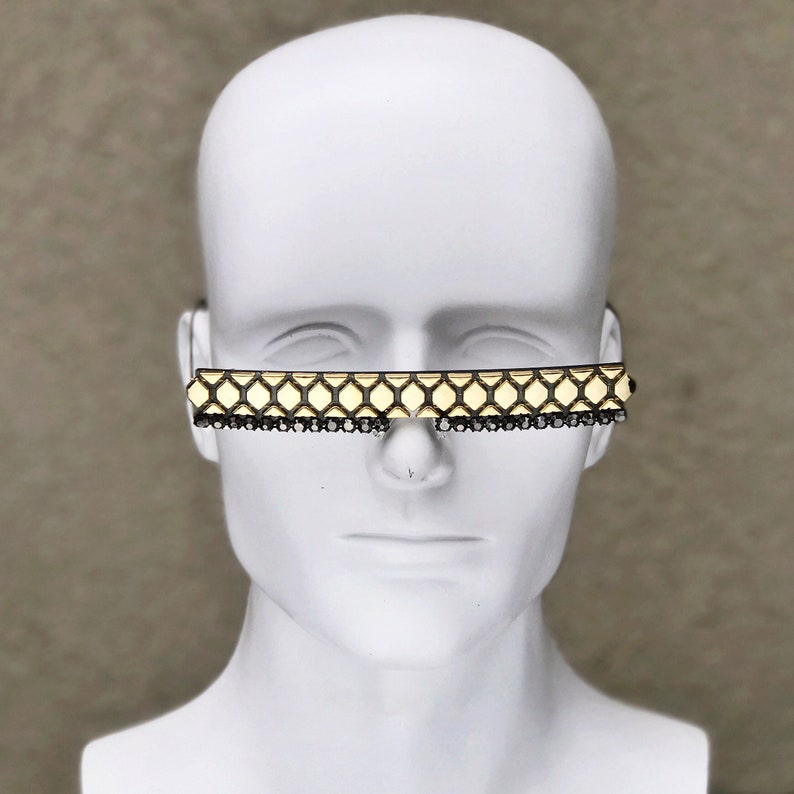 May include: Gold-toned sunglasses with a geometric pattern and black rhinestone accents.