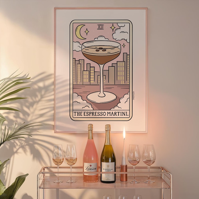 Puede incluir: Una ilustraci&oacute;n de carta de tarot con fondo rosa y una copa de espresso martini. La carta se titula "The Espresso Martini" y tiene el n&uacute;mero XII. La carta est&aacute; enmarcada y colgada en una pared.