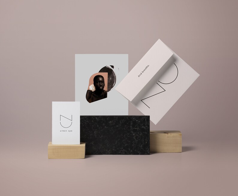 May include: A black and white illustration of a stylized face with a circle and a triangle. The illustration is on a white card with the text "And breathe." The card is on top of a black and white textured surface. A white card with the text "CZ urban spa" is on a wooden surface.