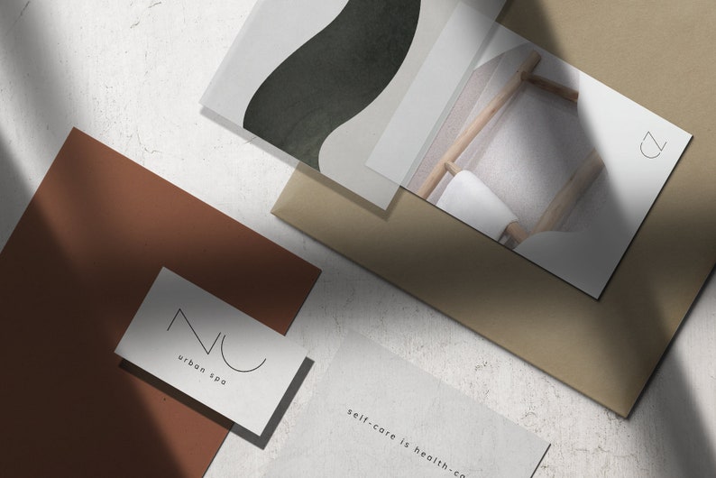 May include: A flat lay of branding materials for a spa. The image features a brown card with the text "NU urban spa" in black lettering, a white card with the text "self-care is health-co" in black lettering, a white card with a black abstract design, and a white card with a photo of a wooden chair with a white towel on it and the letter "Z" in black lettering.