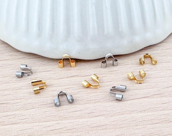 Puede incluir: Una colección de cuentas de crimpado de metal dorado y plateado. Las cuentas son pequeñas y tienen forma de U. Se utilizan para la elaboración de joyas.