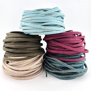 Puede incluir: Cuatro carretes de cordón de tela de corcho en diferentes colores: azul claro, verde oscuro, beige claro y azul verdoso. El cordón está cosido con un hilo de contraste.