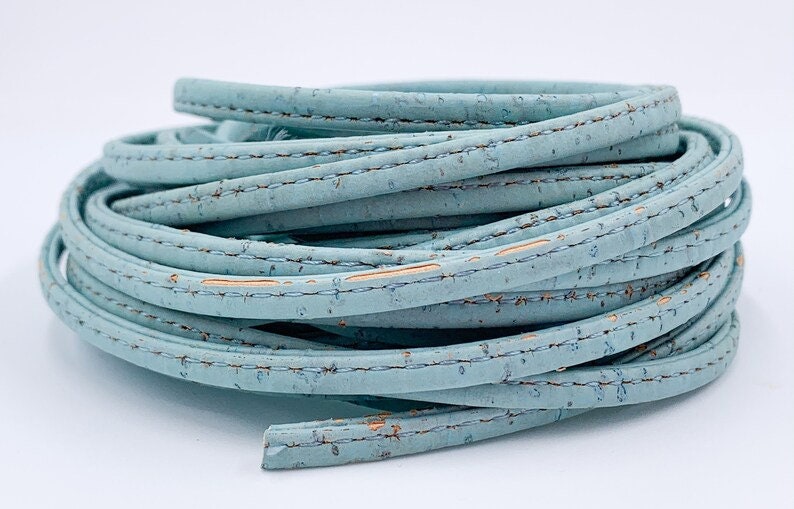 May include: A roll of light blue cork cord with a stitched edge. The cord is made from natural cork and has a subtle texture.