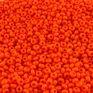 May include: A large quantity of small, round, orange seed beads. The beads are opaque and have a smooth, glossy finish.