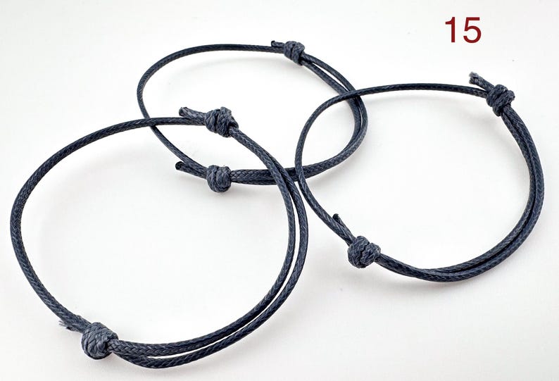 May include: Three adjustable navy blue cord bracelets with knotted closures. The bracelets are circular and appear to be made of a durable, woven material. The number "15" is visible in the upper right corner.