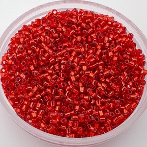 Könnte beinhalten: Eine Schale gefüllt mit kleinen, roten Glasperlen. Die Perlen haben einen metallischen Glanz und sind perfekt für die Schmuckherstellung.