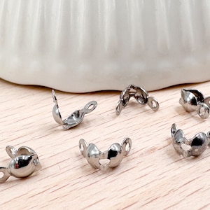 Op de afbeelding: Zes zilveren metalen sluitingen voor het maken van sieraden. De sluitingen zijn hartvormig met een kleine lus aan elke kant.