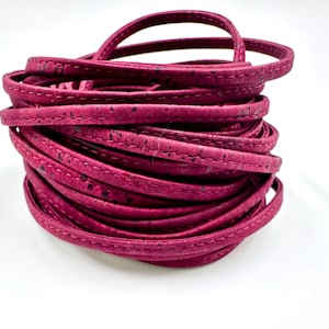May include: A roll of pink cork leather cord with a stitched edge. The cord is approximately 5mm wide.