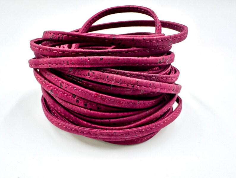 May include: A roll of pink cork leather cord with a stitched edge. The cord is approximately 5mm wide.