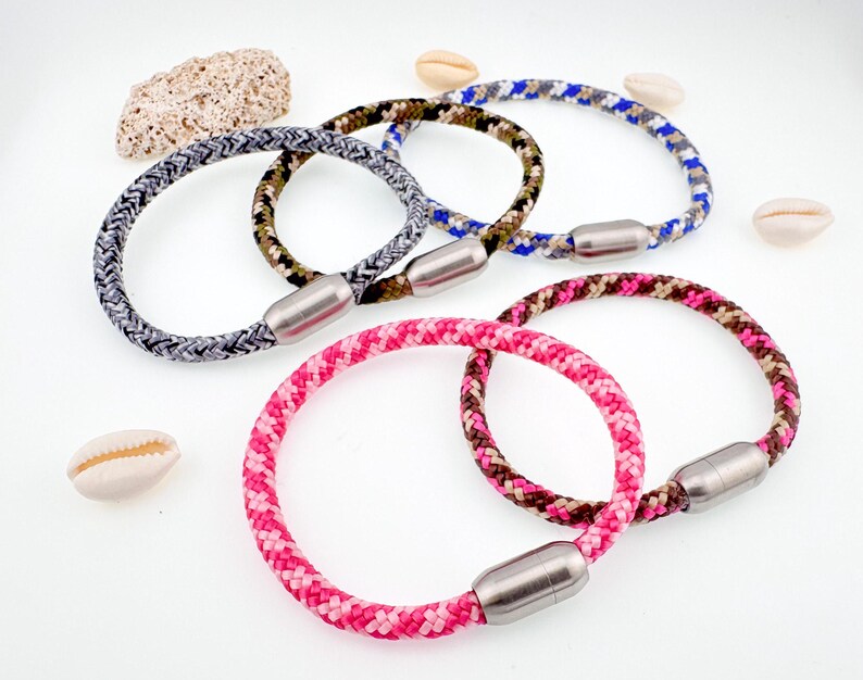 Puede incluir: Cuatro pulseras de cuerda de colores con cierres magn&eacute;ticos. Las pulseras son grises, azules, verdes y rosas.