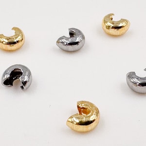 Könnte beinhalten: Fünf Quetschperlen, zwei goldfarben und drei silberfarben, zum Schmuck basteln.