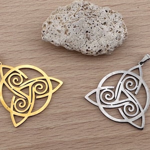 Pode incluir: Dois pingentes com um design de nó celta. Um pingente é dourado e o outro é prateado.