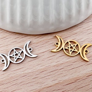 Könnte beinhalten: Zwei Metall-Anhänger in Form eines dreifachen Mondes mit einem Pentagramm in der Mitte. Ein Anhänger ist silberfarben und der andere goldfarben.