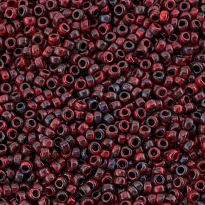 Könnte beinhalten: Nahaufnahme einer großen Menge kleiner, runder, roter und schwarzer Perlen. Die Perlen sind aus Keramik und haben eine glänzende Oberfläche.