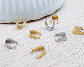 Puede incluir: Una colección de anillas de salto doradas y plateadas, también conocidas como baúles de colgantes, que se utilizan para sujetar dijes o colgantes a collares o pulseras.